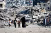 Bildet viser palestinere som går forbi ruiner på Gaza. Foto: Mahmoud Issa / Reuters / NTB