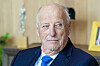 Kong Harald sitter i et kontorrom med lyse treflater og blå dress.