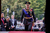 Kongefamilien går på rød løper foran Stortinget, med kong Haakon VIII i militæruniform i front.
