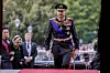 Kongefamilien går på rød løper foran Stortinget, med kong Haakon VIII i militæruniform i front.