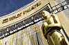 Gullfarget Oscar-statuett foran inngangen til Dolby Theatre under en klar himmel.