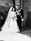 Kronprins Harald og kronprinsesse Sonja poserer i et rom på Slottet med brudekjole, uniform og bukett.