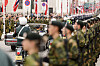 Kongebil og militært følge kjører forbi soldater som står oppstilt langs en gate i Oslo.