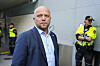 Trygve Slagsvold Vedum står foran en bygning, med to politibetjenter i refleksvester i bakgrunnen.
