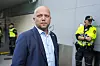Trygve Slagsvold Vedum står foran en bygning, med to politibetjenter i refleksvester i bakgrunnen.