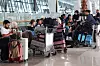 Reisende sitter og står ved bagasje i en terminal mens flyplassen er stengt.
