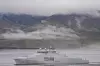 Grått kystvaktskip ved kai foran fjell og tåke i Longyearbyen på Svalbard.
