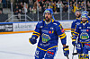 Ishockeyspiller i blå Storhamar-drakt på isen med kølle, med medspillere og publikum i bakgrunnen.