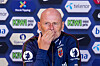 Ståle Solbakken sitter foran en sponsorvegg med logoer og dekker munnen med hånden.
