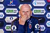 Ståle Solbakken sitter foran en sponsorvegg med logoer og dekker munnen med hånden.