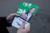 Hender holder en grønn valgflyer med bilde av en Yabloko-kandidat og russisk tekst.