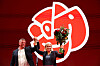 Magdalena Andersson og Tobias Baudin står foran et stort rødt partisymbol og feirer valgresultatet.