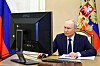 Vladimir Putin sitter ved en datamaskin og stemmer elektronisk i et rom med russiske flagg.