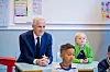 Statsminister Jonas Gahr Støre sitter ved en skolepult sammen med elever i et klasserom.