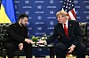 Donald Trump og Volodymyr Zelenskyj sitter og håndhilser foran FN-bakgrunn i New York.