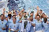 Manchester City-spillere jubler med Premier League-troféet mens blå konfetti fyller luften.
