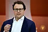 Dario Amodei står på en scene og taler under en debatt, med oransje bakgrunn.