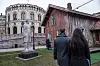 Trehuset «House of Commons» står foran Stortinget i Oslo, med to personer i forgrunnen.