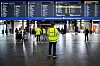 Streikevakter i gule vester står i hallen på Oslo S under avgangstavler.