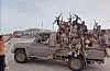 Houthi-krigere står på en pickup med våpen hevet i Khawkhah, Yemen.