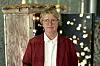 Marianne Heske står foran et kunstverk med små hus under utstillingen «Kroppen i kunsten».