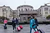 Trehuskunst foran Stortinget i Oslo med hengelås på døren, omgitt av forbipasserende med kofferter.