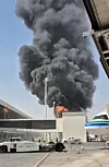 Svart røyk og flammer stiger over terminalbygninger og kjøretøy på Riyadh-flyplassen.