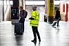 Streikevakt i gul refleksvest står i avgangshallen på Oslo S blant reisende og bagasje.