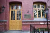 Rød teglfasade ved Bjørknes Privatskole med gule dører, vinduer og inngangsskilt.