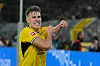 Nico Schlotterbeck i gul Dortmund-drakt feirer en scoring foran tribuner og reklameskilt.