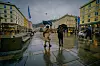 Våte brosteiner og fotgjengere med paraplyer på Torgallmenningen i Bergen.