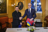 Jonas Gahr Støre og Volodymyr Zelenskyj håndhilser i representasjonsboligen med norske og ukrainske flagg på et bord foran dem i Oslo.
