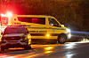 Gul ambulanse og politibil med blålys på en regnvåt vei i Ringerike om natten.