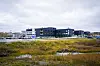 Kirkenes sykehus ligger bak et myrlandskap med vannspeil under en overskyet himmel.
