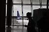 SAS-fly sett gjennom vinduene på Oslo lufthavn, med en reisende i silhuett i forgrunnen.