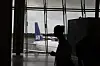 SAS-fly sett gjennom vinduene på Oslo lufthavn, med en reisende i silhuett i forgrunnen.
