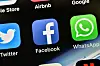 Nærbilde av Facebook- og WhatsApp-ikonene på en iPhone, med andre appikoner rundt.