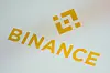 Binance-logo og oransje tekst på en lys smarttelefonskjerm.