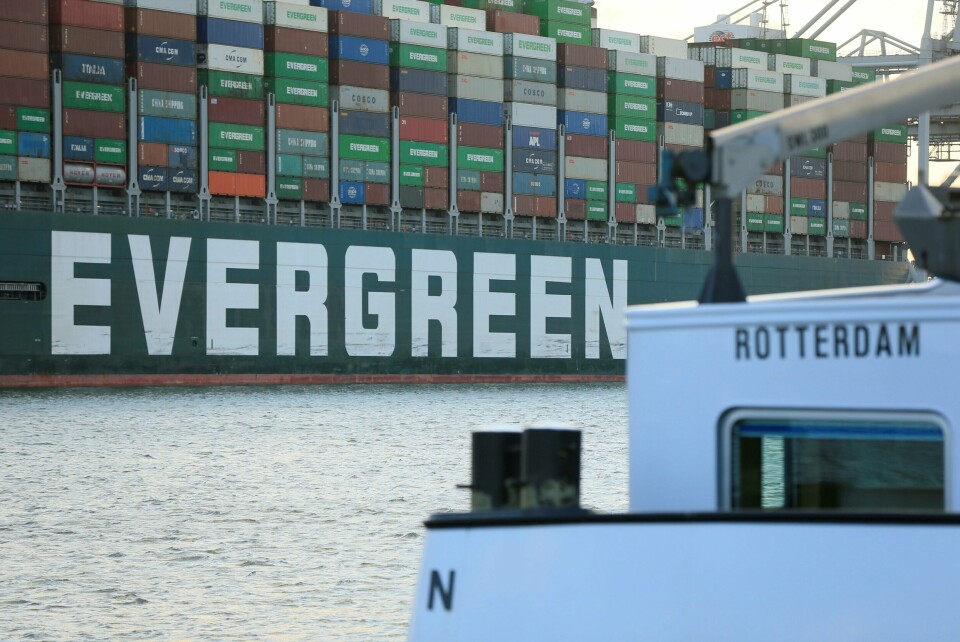 FRAMME: Ever Given er framme i Rotterdam etter nesten fem måneder. Bildet er av den ene siden av skipet Ever Given. Det står Evergreen i hvitt på siden av det mørkegrønne skipet som er lastet med store mengder konteinere i ulike farger. I forgrunnen av bildet er også en liten hvit båt der det står Rotterdam. Foto: Eva Plevier / Reuters / NTB