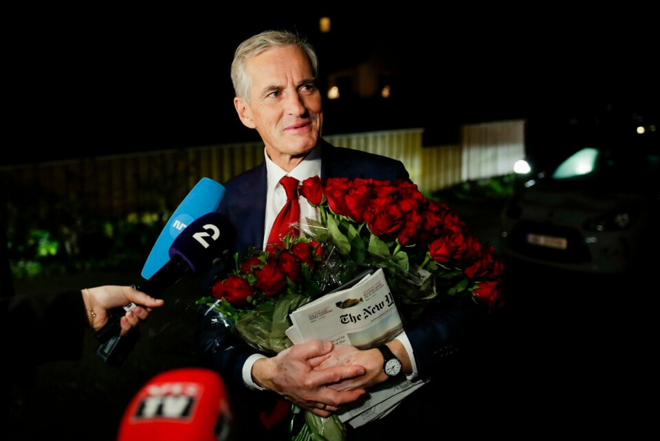 TID: Jonas Gahr Støre sier han vil bruke tid på å lage en ny regjering. Målet er at han kan starte jobben for fullt fra neste uke. Bildet er av Ap-leder Jonas Gahr Støre. Han snakker i flere mikrofoner mens han holder en avis og buketter med røde roser. Det er mørk natt i bakgrunnen. Foto: Javad Parsa / NTB