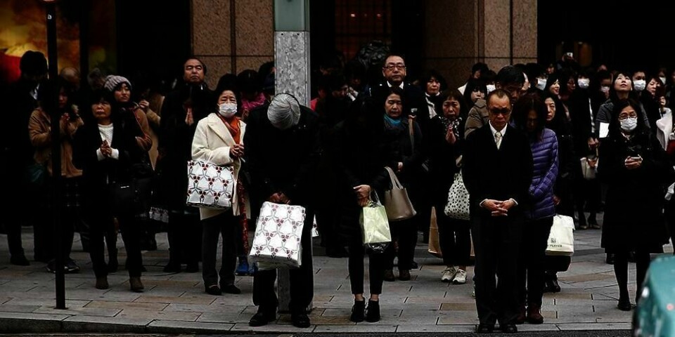 MINTES: Japanere mintes fredag at det har gått fem år siden jordskjelvet i 2011. Jordskjelvet startet en tsunami. Bildet viser folk på et gatehjørne i Tokyo. De holder ett minutts stillhet til minne om de 18.500 som døde.