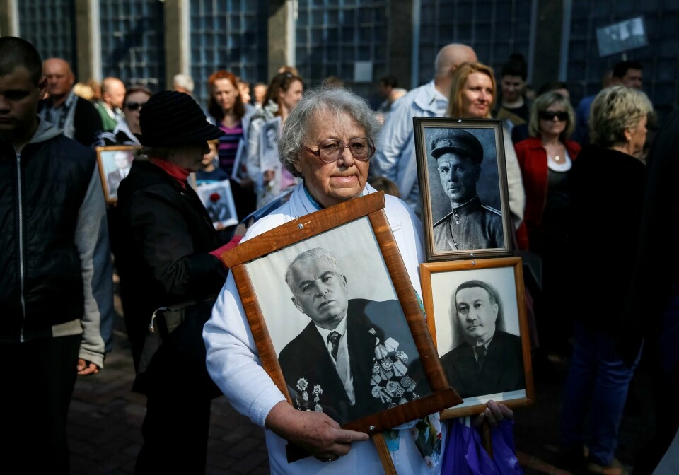 SORG: Det er 71 år siden andre verdenskrig var over. En kvinne i Ukraina bærer bilder av familiemedlemmer som ble drept under krigen.