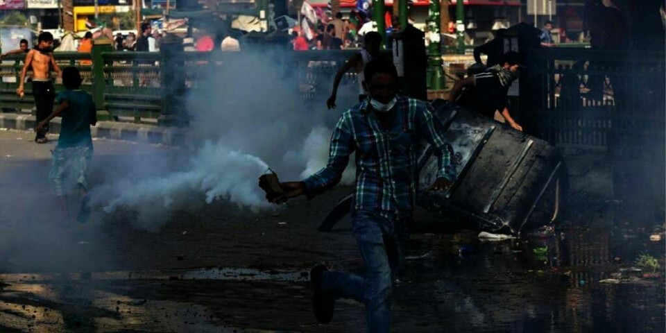 SINTE: En demonstrant holder en boks tåregass som politiet har kastet mot dem. Flere demonstrerte utenfor den amerikanske ambassaden i Kairo i Egypt torsdag. De er sinte over den islam-kritiske filmen «The Innocence of Muslims». Over 200 personer ble skadd. Egyptiske islamister varsler nye, store demonstrasjoner fredag.