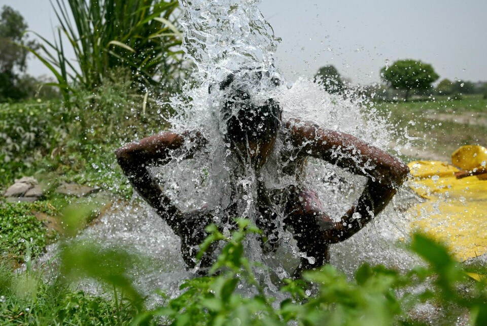 VARMT: New Dehli i India er varm. Folk må takle en temperatur på over 50 grader. Bildet viser en mann i New Dehli som kjøler seg ned med vann.