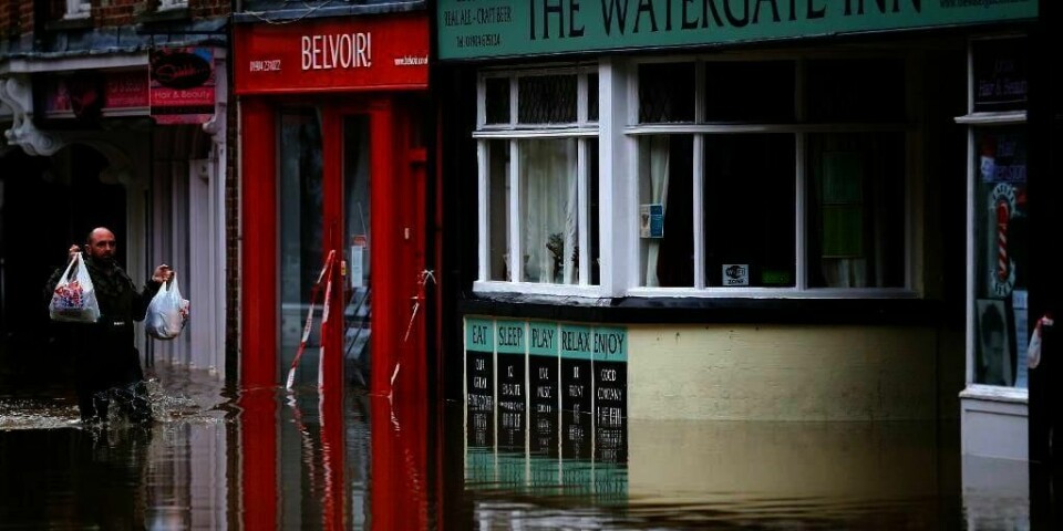 FLOM: En mann bærer matvarene sine inn til en oversvømt pub i byen York.