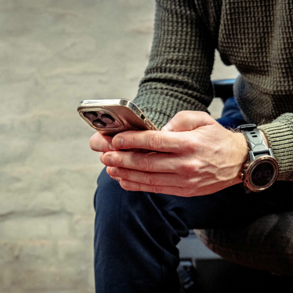 TILGJENGELIG: Mange mener jobben går utover privatlivet. Noen føler de alltid må være tilgjengelige. Bilde av mann som holder mobiltelefon.Foto: Emilie Holtet / NTB