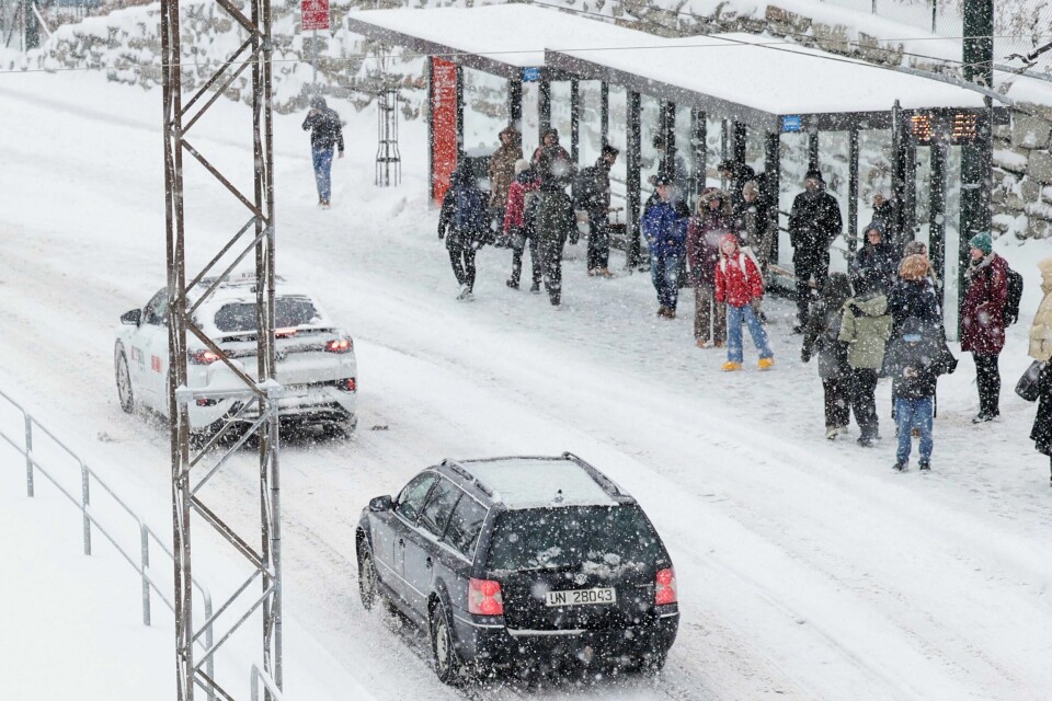 BERGEN: Snøvær fører til forsinkelser i Bergen fredag. Kanskje må du vente ekstra lenge på bussen? Bildet viser folk som venter på bussen i et busskur i Bergen.