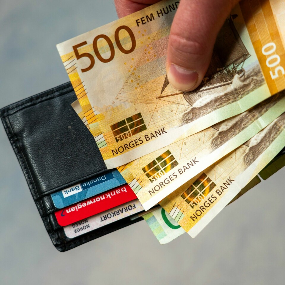 ØKONOMI: Månedslønna vokste i snitt med 6 prosent på ett år. Bildet viser en hånd som holder en lommebok med bankkort og 500-lapper. Foto: Gorm Kallestad / NTB