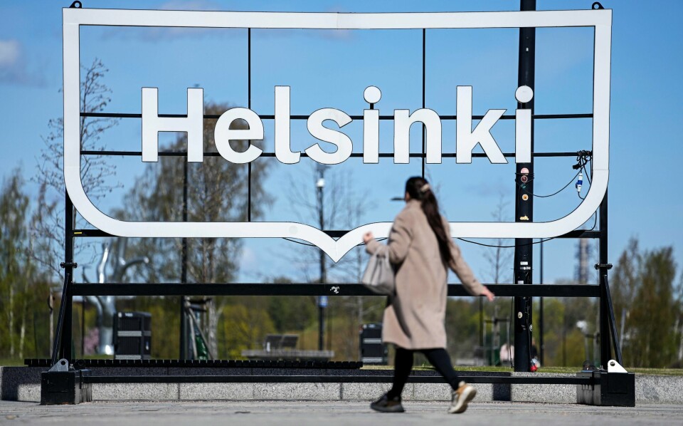 LYKKELIGST: Finland er på førsteplass i FNs nye lykkemåling. Bilde av dame foran Helsinki-skilt. Foto: Ap / NTB