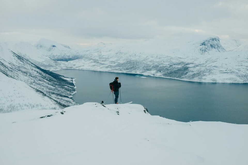 FJELLVETT: Turer i fjellet er flott. Men det er viktig å huske på sikkerheten. Da kommer fjellvettreglene godt med. Bildet viser en mann som ser på utsikten over et fjellvann fra en fjelltopp. Foto: Anders Stensland Olsen